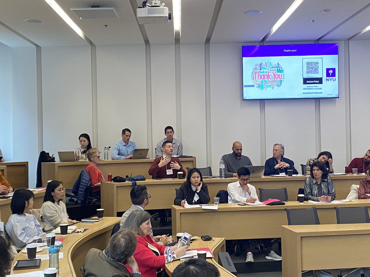 Attendees seated in a tiered classroom, one asking a question, at the 2nd MEM Conference